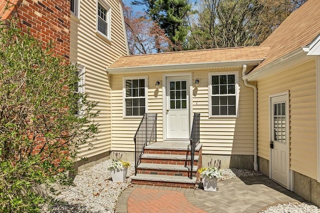 doorway to property with roof with shingles
