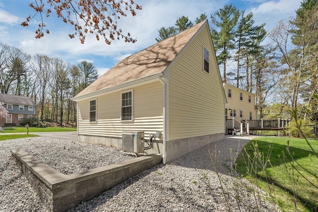 view of property exterior featuring a lawn, central AC, and a deck