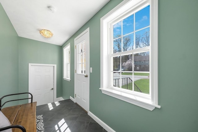 entryway featuring dark tile patterned flooring and baseboards