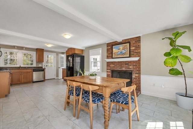 dining area with baseboards, a brick fireplace, and beam ceiling