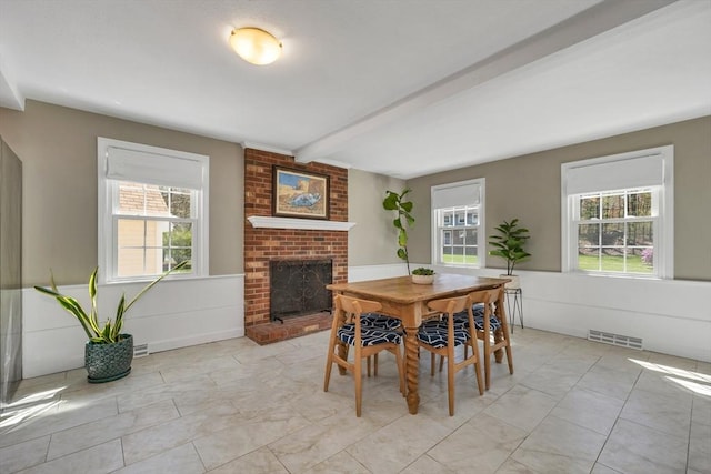 dining space featuring visible vents, plenty of natural light, beam ceiling, and a fireplace