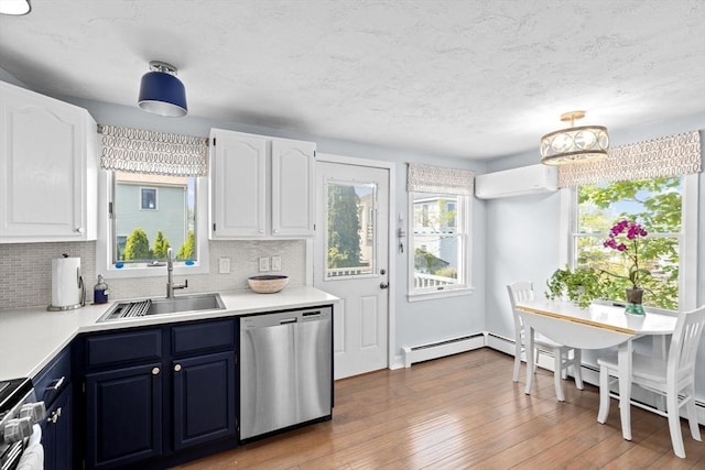 kitchen featuring dishwasher, a sink, blue cabinetry, a wall mounted AC, and light countertops