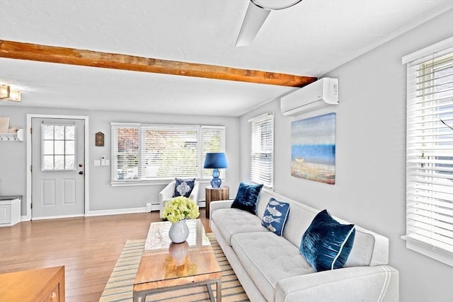 living room with wood finished floors, an AC wall unit, beamed ceiling, healthy amount of natural light, and baseboards