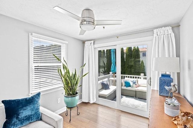 sitting room featuring healthy amount of natural light, wood finished floors, a ceiling fan, and baseboards