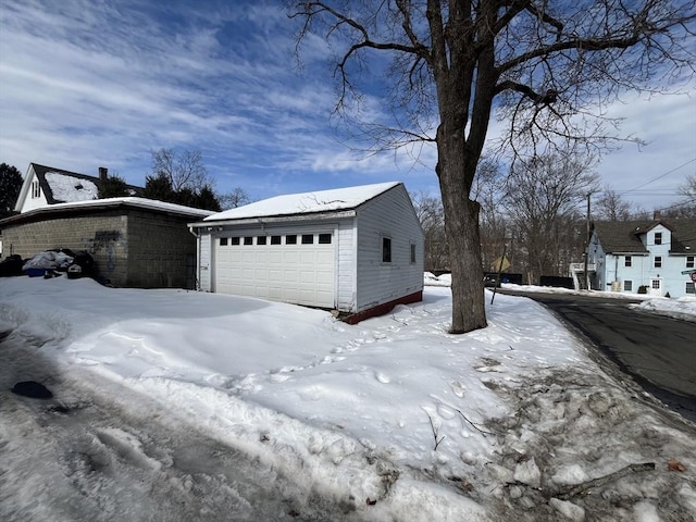 view of snow covered exterior featuring a detached garage and an outdoor structure