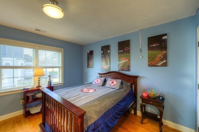 bedroom featuring baseboards, visible vents, and wood finished floors