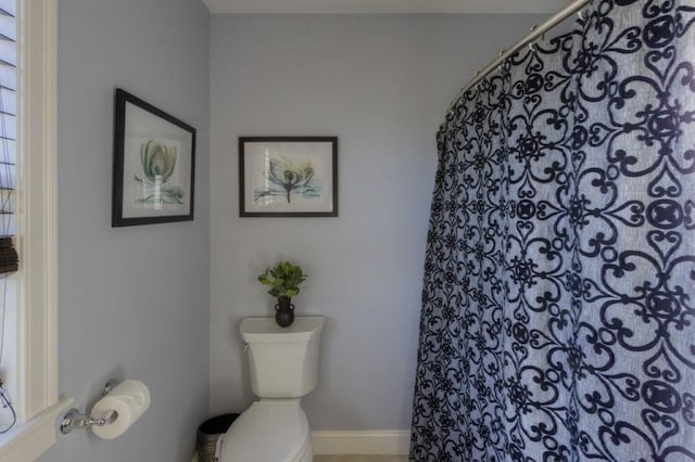 full bath featuring toilet, baseboards, and a shower with curtain