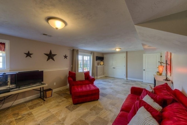 living area featuring baseboards, a textured ceiling, and visible vents