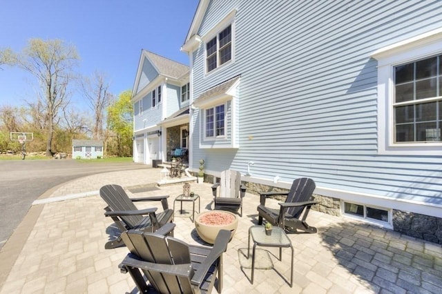 view of patio with a garage and an outdoor fire pit