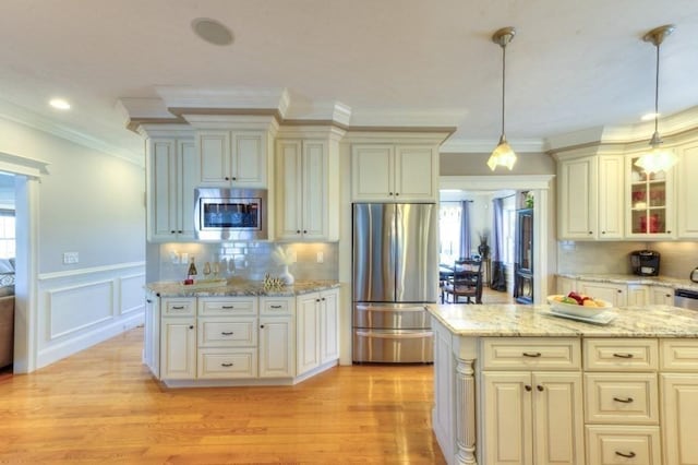 kitchen with pendant lighting, light wood finished floors, glass insert cabinets, and stainless steel appliances