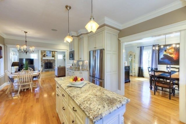 kitchen featuring a stone fireplace, freestanding refrigerator, plenty of natural light, and a chandelier