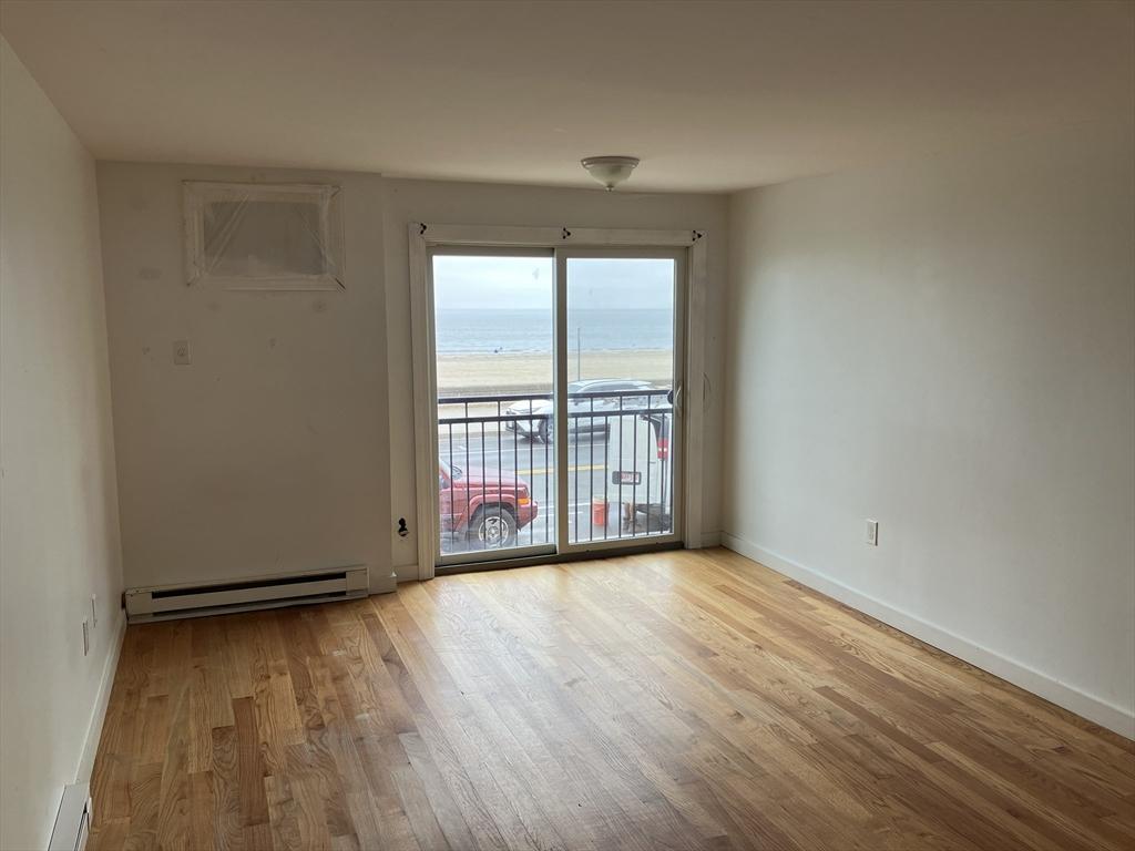 383 Revere Beach Blvd Unit 5, Revere, MA 02156 - spare room with a baseboard radiator, wood finished floors, view of water and beach, and baseboards