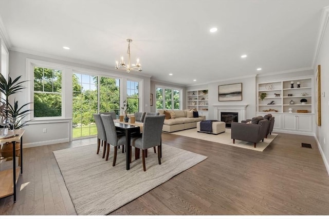 dining room featuring a chandelier, crown molding, built in features, and hardwood / wood-style floors