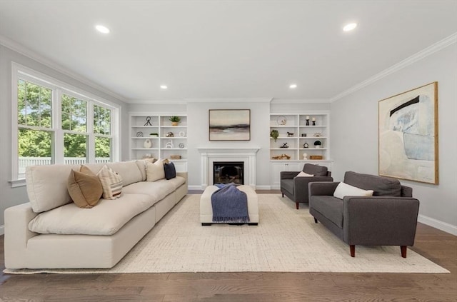 living room featuring built in shelves, crown molding, and hardwood / wood-style flooring