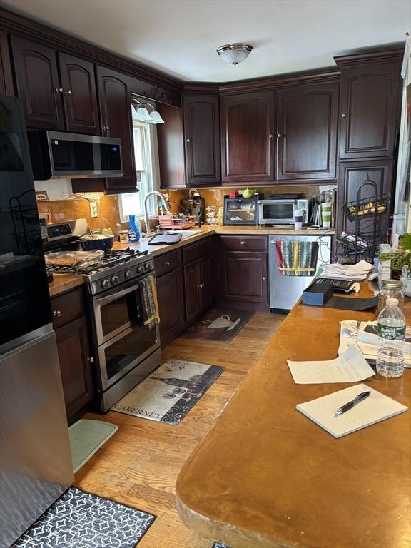 20 Osgood Ave, Lowell, MA 01850 - kitchen with appliances with stainless steel finishes, light wood finished floors, dark brown cabinetry, and light countertops