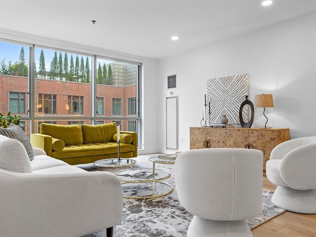 living area with a wall of windows, recessed lighting, and wood finished floors