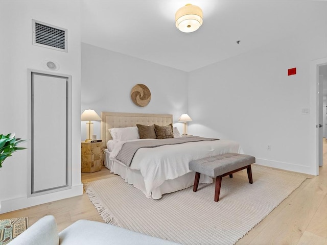 bedroom with visible vents, baseboards, and wood finished floors