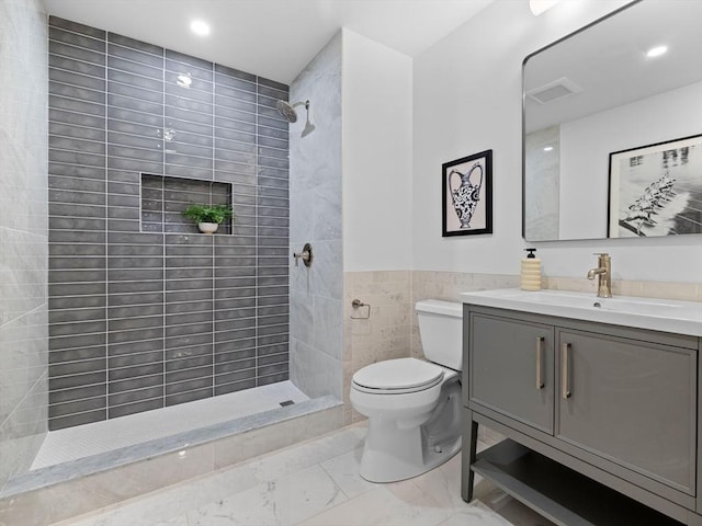 full bath with vanity, tiled shower, tile walls, toilet, and marble finish floor