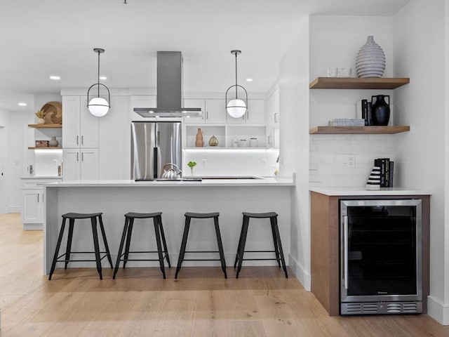 kitchen featuring beverage cooler, open shelves, freestanding refrigerator, white cabinets, and island range hood