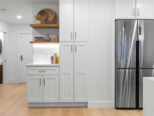 kitchen with light wood-style flooring, open shelves, freestanding refrigerator, white cabinets, and light countertops