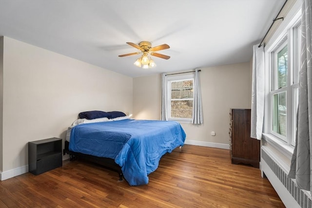 bedroom with radiator, multiple windows, and wood finished floors