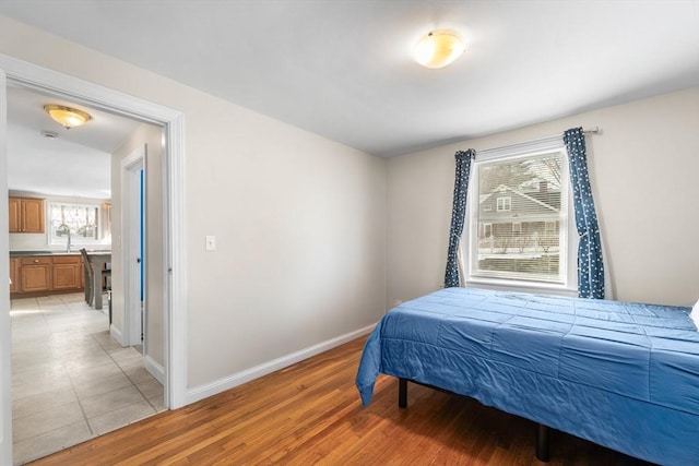 bedroom featuring light wood finished floors, baseboards, and a sink