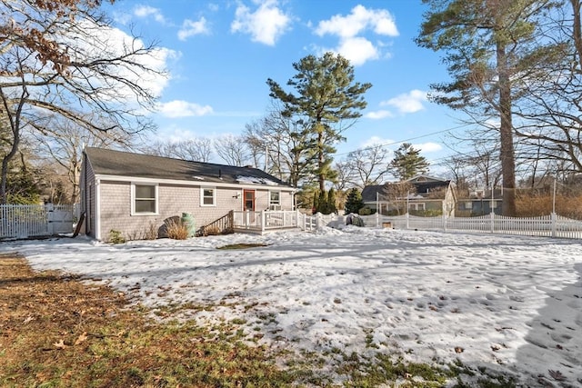 snow covered house with fence and a deck