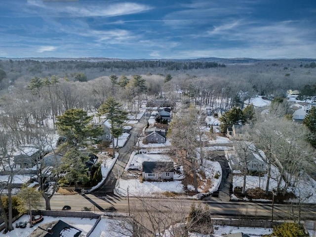 snowy aerial view featuring a wooded view