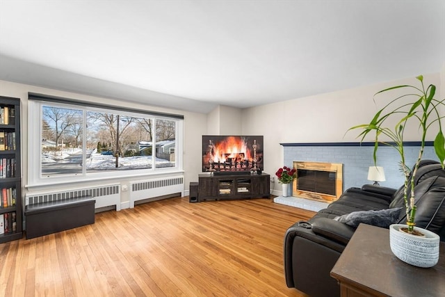 living room with radiator, wood-type flooring, and a fireplace