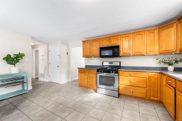 kitchen with dark countertops, gas range, black microwave, and brown cabinetry