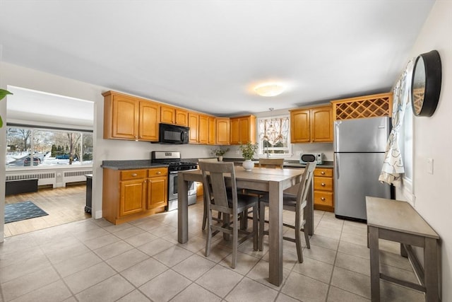 kitchen featuring stainless steel appliances, light tile patterned flooring, plenty of natural light, and radiator heating unit