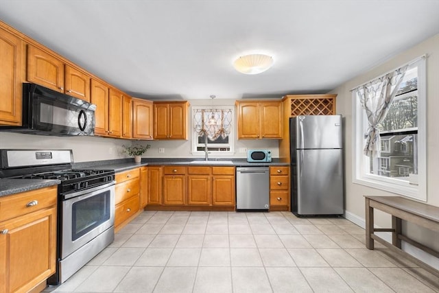 kitchen featuring appliances with stainless steel finishes, dark countertops, brown cabinets, and light tile patterned floors