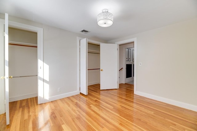 unfurnished bedroom with visible vents, light wood-style floors, multiple closets, and baseboards