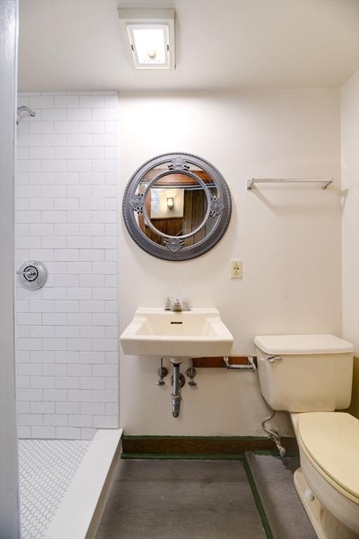 full bathroom featuring a stall shower, toilet, and a sink