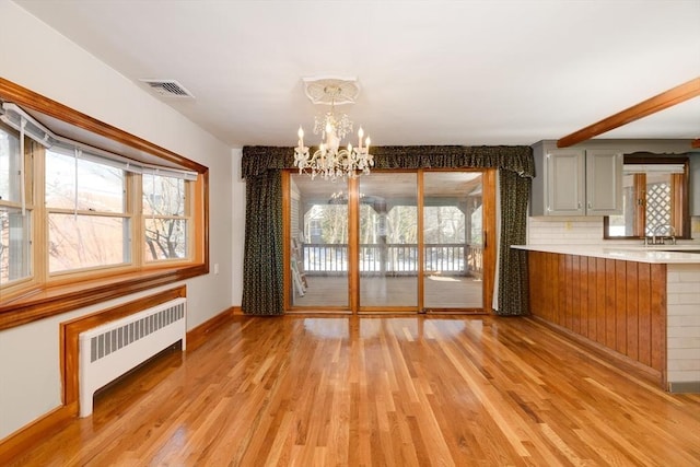 unfurnished dining area featuring a wealth of natural light, visible vents, light wood-style flooring, and radiator heating unit