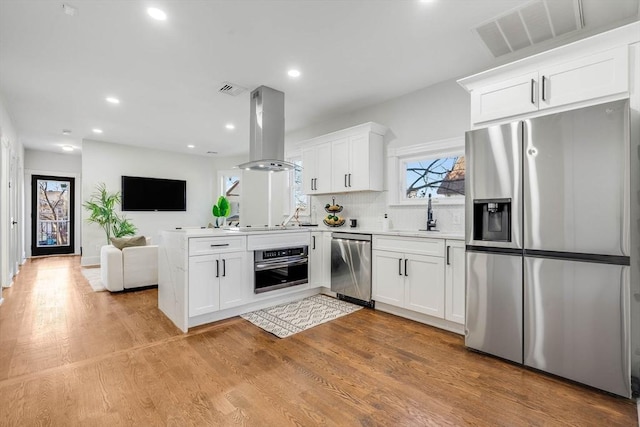 kitchen featuring white cabinets, sink, island exhaust hood, and stainless steel appliances