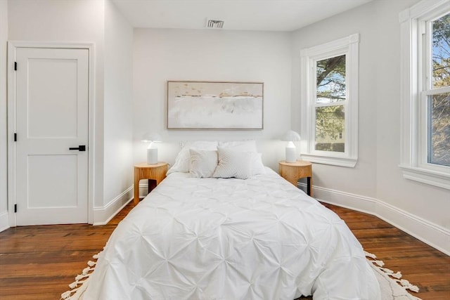 bedroom with multiple windows and dark hardwood / wood-style flooring