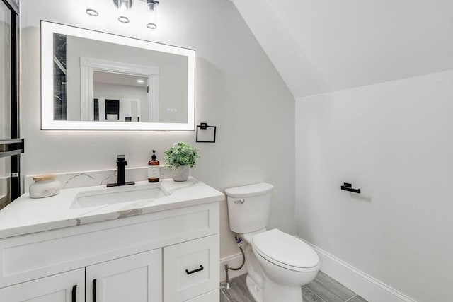 bathroom featuring vanity, toilet, and lofted ceiling