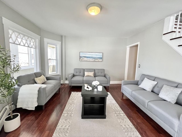 living area with a baseboard heating unit, stairway, baseboards, and wood finished floors
