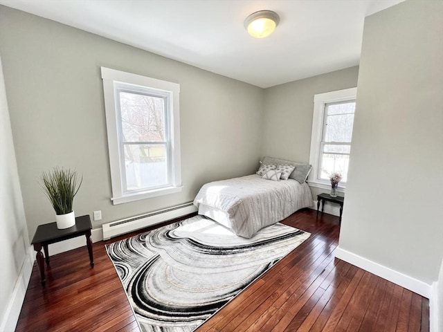 bedroom with a baseboard heating unit, dark wood-style flooring, and baseboards