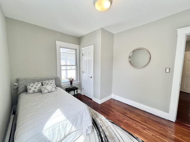 bedroom featuring a baseboard heating unit, baseboards, and wood finished floors
