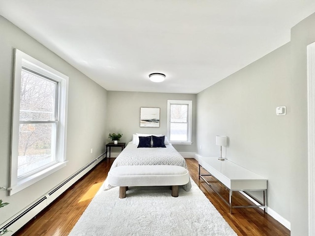 bedroom with wood finished floors, baseboards, and a baseboard heating unit