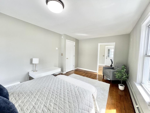 bedroom with a baseboard heating unit, baseboards, and wood finished floors