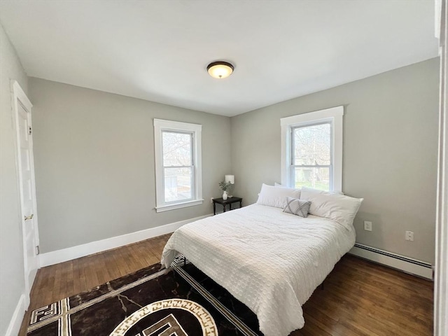 bedroom with baseboards, multiple windows, a baseboard radiator, and dark wood-type flooring