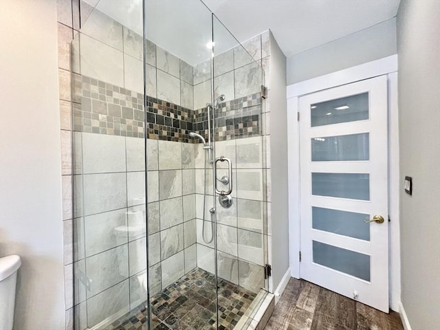 bathroom with toilet, a shower stall, and wood finished floors