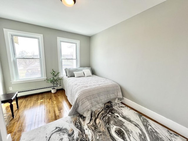 bedroom featuring baseboards, hardwood / wood-style floors, and baseboard heating