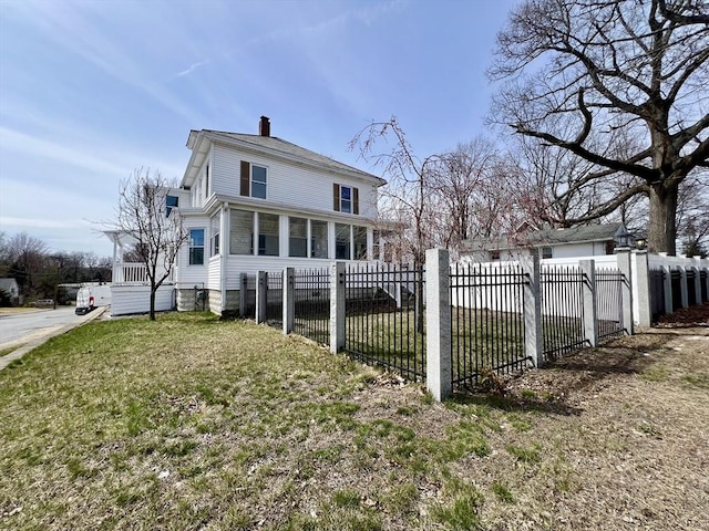 back of property with a chimney, fence private yard, and a lawn