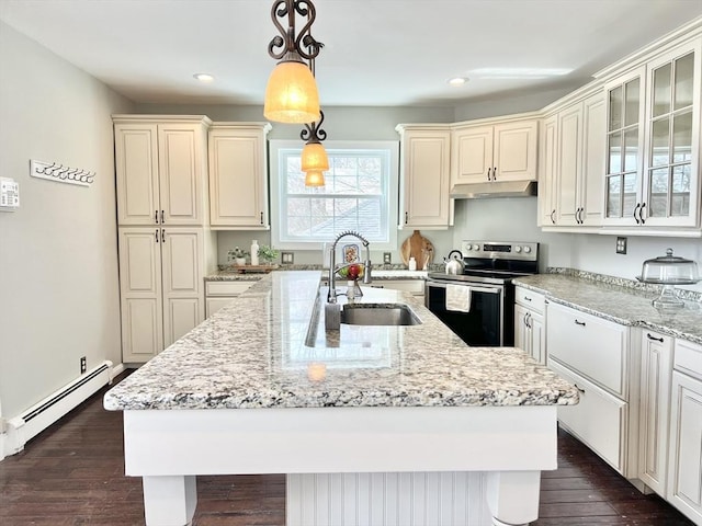 kitchen featuring a baseboard radiator, under cabinet range hood, a sink, stainless steel range with electric cooktop, and a center island with sink