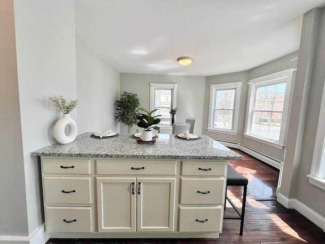 kitchen with baseboards, a baseboard heating unit, light stone counters, white cabinetry, and a peninsula