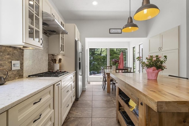 17 Juniper Ln, Framingham, MA 01701 - kitchen featuring under cabinet range hood, decorative backsplash, glass insert cabinets, hanging light fixtures, and light stone counters
